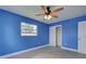 Bright bedroom with blue walls, ceiling fan, gray tile flooring, closet and a window at 1295 S Maryknoll Rd, Englewood, FL 34223