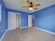 Bright bedroom with blue walls, ceiling fan, gray tile flooring, and closet at 1295 S Maryknoll Rd, Englewood, FL 34223