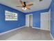 Bright bedroom with blue walls, ceiling fan, gray tile flooring, closet and a window at 1295 S Maryknoll Rd, Englewood, FL 34223