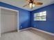 Bright bedroom with blue walls, ceiling fan, gray tile flooring, closet and a window at 1295 S Maryknoll Rd, Englewood, FL 34223