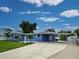 Attractive blue single-story home showcasing an extended driveway and carport with mature landscaping at 1295 S Maryknoll Rd, Englewood, FL 34223