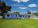 A bright blue single-story home featuring white trim, a green lawn and mature landscaping at 1295 S Maryknoll Rd, Englewood, FL 34223