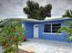 Close-up shot of front door of a blue house with white trim and tropical landscaping at 1295 S Maryknoll Rd, Englewood, FL 34223