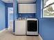 Bright laundry room featuring a white washer and dryer set with overhead cabinets and a natural light filled window at 1295 S Maryknoll Rd, Englewood, FL 34223