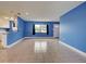 Bright and open living room with tile floors, large windows, and a view into the kitchen area at 1295 S Maryknoll Rd, Englewood, FL 34223