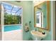 Bathroom with a pedestal sink that opens to a screened pool area at 1415 Bayshore Dr, Englewood, FL 34223