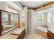 Bright bathroom featuring a soaking tub, large mirror, and vanity with dark wood cabinetry at 1415 Bayshore Dr, Englewood, FL 34223