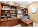Home office featuring custom built-in wooden shelving, desk, and natural light from the window at 1415 Bayshore Dr, Englewood, FL 34223