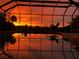 Screened pool reflecting colorful sunset, surrounded by lush tropical foliage at 1415 Bayshore Dr, Englewood, FL 34223