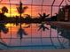 Screened-in pool reflecting a vibrant sunset and palm trees, creating a tranquil oasis at 1415 Bayshore Dr, Englewood, FL 34223
