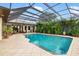 The screened-in pool area features a sparkling pool, lush landscaping, and a covered patio at 1415 Bayshore Dr, Englewood, FL 34223