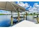 Waterfront property boasting a private boat lift with canopy on a tranquil waterway under a sunny, cloudy sky at 15498 Seafoam Cir, Port Charlotte, FL 33981