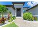 Elegant front entrance with contemporary door, stone accents, and tropical landscaping at 15498 Seafoam Cir, Port Charlotte, FL 33981