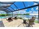 Enjoy serene waterfront views from the screened-in pool area with comfortable seating and lush landscaping at 15498 Seafoam Cir, Port Charlotte, FL 33981