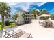 Spacious patio featuring lounge chairs, table with umbrella, and view of the water and palm trees at 1701 Beach Rd # 207, Englewood, FL 34223
