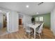 Dining room with a white table and chairs, green accent wall, and wood-look flooring at 1730 Bluebird Ln, Englewood, FL 34224
