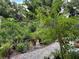 Stone pathway through beautiful garden with various trees, plants, shrubs, and a buddha statue at 1733 Belvidere Rd, Englewood, FL 34223