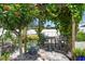 Wooden outdoor seating area under a pergola with mature trees and a white fence at 1733 Belvidere Rd, Englewood, FL 34223