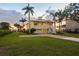 Spacious two-story yellow home boasts lush green lawn and brick driveway leading to the garage at 1784 Bayshore Dr, Englewood, FL 34223