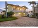 Charming two-story yellow home features a brick driveway, covered porch, and attached garage at 1784 Bayshore Dr, Englewood, FL 34223