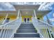 Inviting entryway featuring bright yellow siding, white railings, and charming outdoor lighting at 1784 Bayshore Dr, Englewood, FL 34223