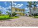 Stunning yellow home with brick driveway, lush landscaping, and convenient garage access at 1784 Bayshore Dr, Englewood, FL 34223