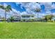 Charming yellow house with expansive green lawn, complemented by lush landscaping and tropical palm trees at 1784 Bayshore Dr, Englewood, FL 34223