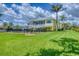 Yellow home with a spacious backyard, screened porch, and lush green lawn under a partly cloudy sky at 1784 Bayshore Dr, Englewood, FL 34223
