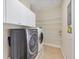 Laundry room offers ample storage with overhead cabinets and shelving, alongside front-load washer and dryer at 1784 Bayshore Dr, Englewood, FL 34223