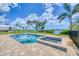 Inviting pool and spa with brick surround and fence, overlooking serene water views and lush greenery at 1784 Bayshore Dr, Englewood, FL 34223