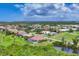 Aerial view of a property with a pool, overlooking lush green space, golf course and beautiful blue skies at 200 Arlington Dr, Placida, FL 33946