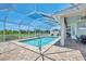 A screened-in outdoor pool has a brick surround, lounge chairs, and a landscaped yard at 200 Arlington Dr, Placida, FL 33946