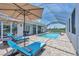 The outdoor pool area features a screened enclosure, brick surround, and lounge chairs with umbrellas at 200 Arlington Dr, Placida, FL 33946