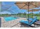 Outdoor pool and patio area features lounge chairs with umbrellas, a screened enclosure and landscaped yard at 200 Arlington Dr, Placida, FL 33946