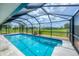 Inviting in-ground pool surrounded by screened enclosure and view of the yard at 2106 Damascus Ln, Punta Gorda, FL 33983