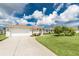 View of the home's front exterior featuring a two-car garage and well-kept landscaping at 25 Mariner Ln, Rotonda West, FL 33947