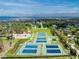 Aerial view of nearby tennis courts, showing the neighborhood, a glimpse of the bay, and lush greenery at 348 W Wentworth St, Englewood, FL 34223