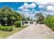 Charming home exterior with a new dark blue front door, modern windows, landscaping, gravel driveway and a shed at 348 W Wentworth St, Englewood, FL 34223