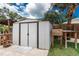 Backyard shows a metal shed with double doors for garden equipment storage, next to a wooden potting table at 348 W Wentworth St, Englewood, FL 34223