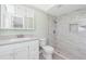 Bathroom featuring marble look tile shower, toilet, sink and white cabinetry at 39 Caddy Rd, Rotonda West, FL 33947