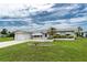 Inviting single-story home showcasing a well-maintained lawn, a charming flowerbed, and an attached single-car garage at 39 Caddy Rd, Rotonda West, FL 33947