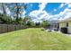 Spacious grassy backyard with a privacy fence, lush trees, and a screened-in pool at 4221 Ulster Ave, North Port, FL 34287