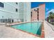 Community pool with a brick paver deck and partial view of the building's exterior at 50 Meredith Dr # 9, Englewood, FL 34223