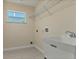 Practical laundry room with tile floors, utility sink, and convenient overhead shelving at 5781 Elton Rd, Venice, FL 34293