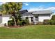 Inviting home with a well-maintained lawn, mature palm, and a covered entryway with stylish architectural detail at 609 Deerwood Ave, Englewood, FL 34223
