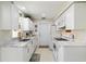 Galley kitchen featuring white cabinets, marble countertops, stainless sink, and white appliances at 609 Deerwood Ave, Englewood, FL 34223