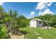 A beautiful backyard with a tool shed, green grass, various foliage, and a sunny sky at 7059 Quigley St, Englewood, FL 34224