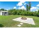 A spacious backyard features a brick fire pit with a tile surround, lush grass, and foliage at 7059 Quigley St, Englewood, FL 34224