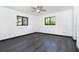 Bright bedroom with dark gray wood flooring, white walls, black window trim, and a ceiling fan at 7059 Quigley St, Englewood, FL 34224