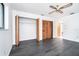 This bedroom features a ceiling fan, wooden closet doors and grey hardwood flooring at 7059 Quigley St, Englewood, FL 34224